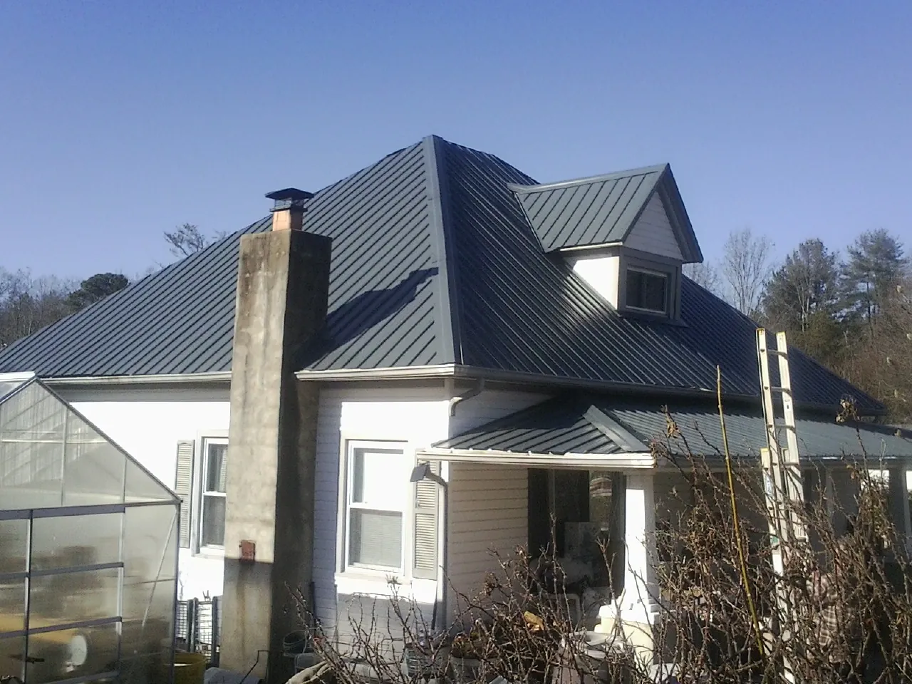 Dark blue standing seam metal roof on a white farmhouse with dormer — Slate & Tile Roof Repair by Roofing Brothers in Hackettstown