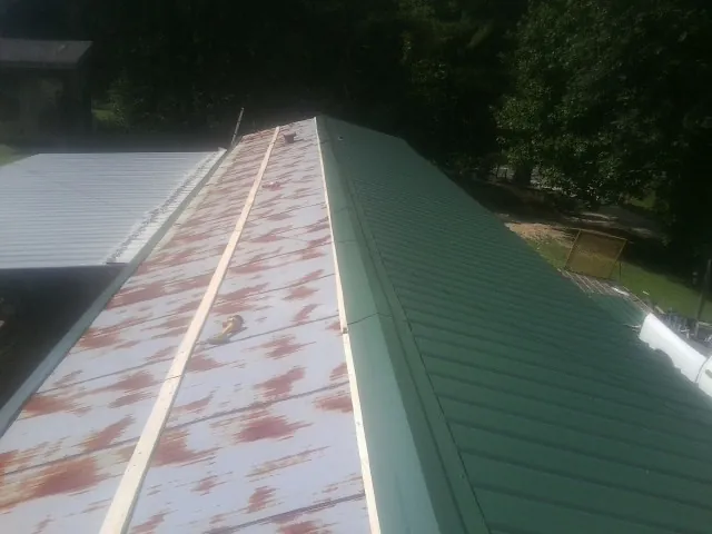 Old rusted panels beside newly installed green metal roofing — Wind Damage Roof Repair by Roofing Brothers in Hackettstown