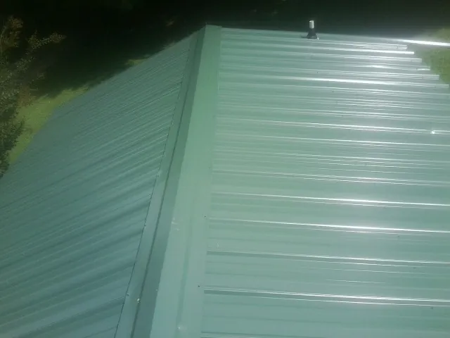 New green metal panels meeting at the ridge of a roof — Flat Roof Repair work by our crew in Hackettstown