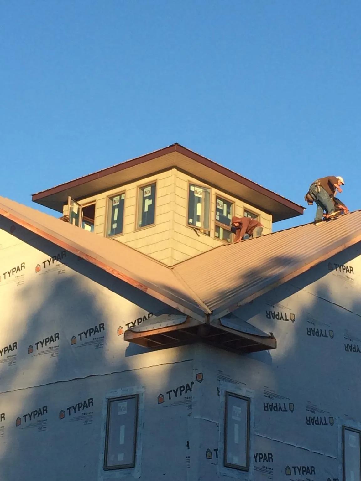 Roofers working around a rooftop cupola on a new metal roof at sunset — Roof Waterproofing in Hackettstown by Roofing Brothers